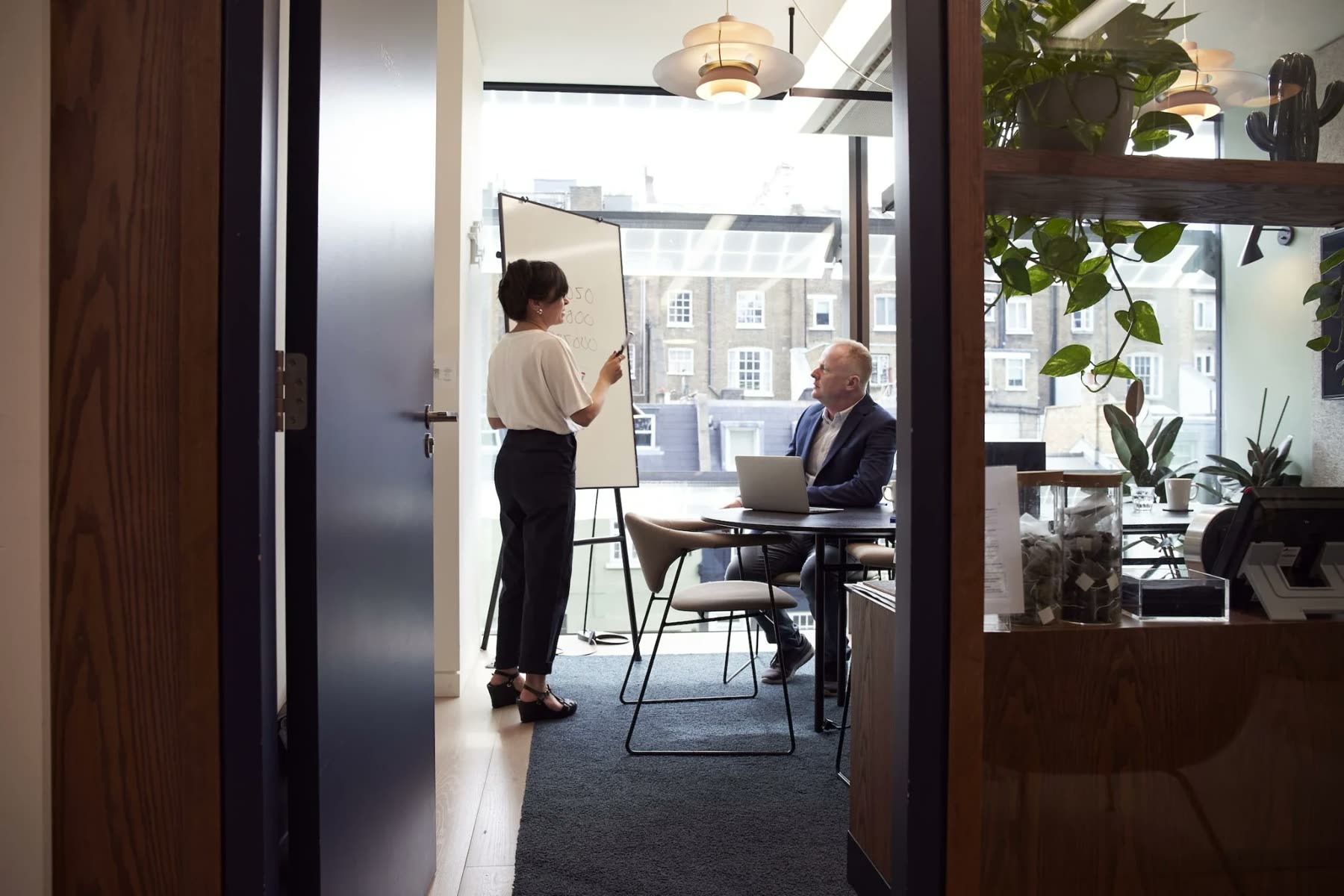 Two colleagues meeting in an office, seen through an open door